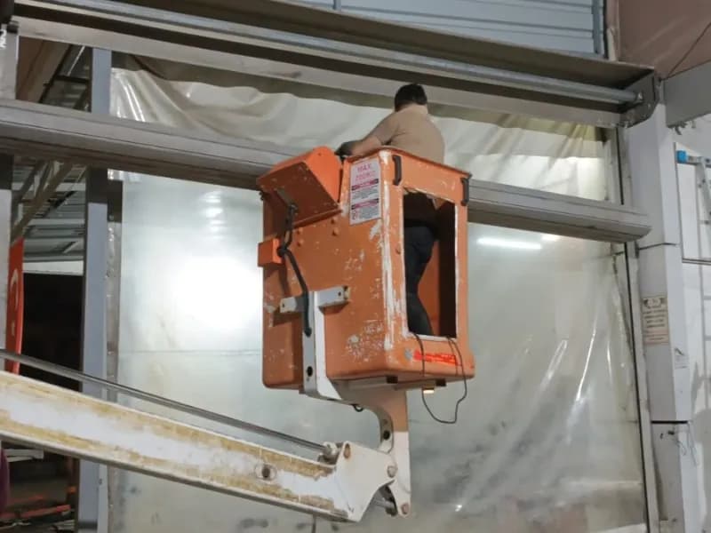 Yükseltici platformda kapı montajı yapan teknisyen